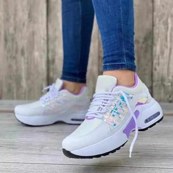 Women's sneakers in a white and purple design with shimmering details, worn with blue jeans. Fashionable sneakers, ideal for leisure and sport.