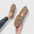 Brown, fluffy women's faux fur loafers, worn with blue jeans. Comfortable, fashionable shoes for fall and winter.